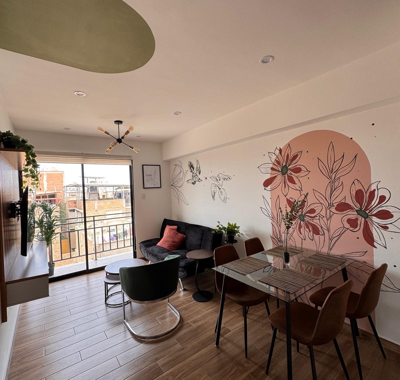 Sala y comedor de Urban Spring, con mural floral y balcón
